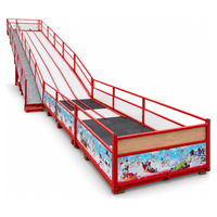 Piste de luge synthétique vue de trois quarts, couloirs blancs, garde-corps rouges et panneaux décorés de Noël